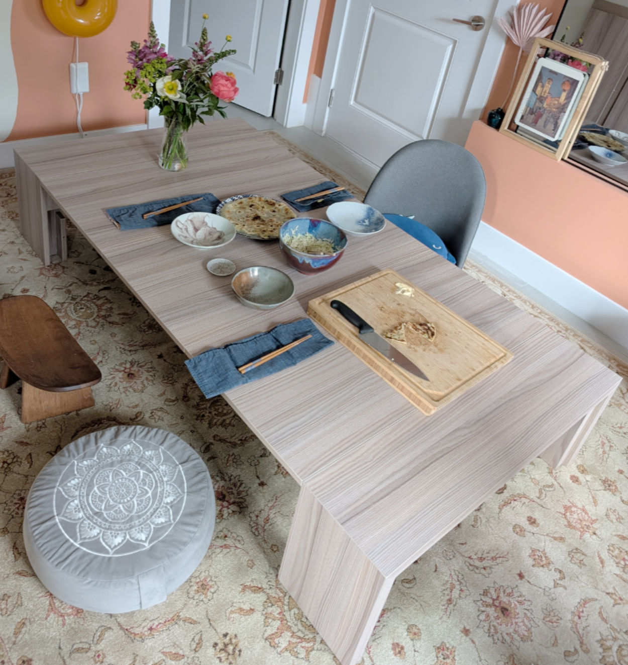 a light wood table with a vase of flowers and food on it